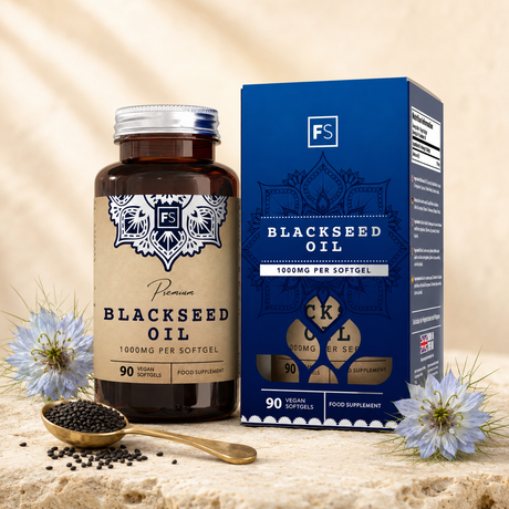 Premium svartfrøolje i brun glassflaske med sølvhette og blå boks, omgitt av svarte frø og blomster.