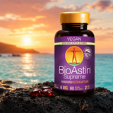 BioAstin Supreme astaxantin i en brun plastflaske med gul lokk, seks røde softgels på svart stein, horisont med solnedgang.
