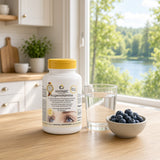 Øyevitaminer i hvit plastflaske med gul lokk, plassert på et trefat ved siden av et glass med vann og en skål med blåbær.