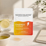 Wellnessplasterpakken "Energy Active Boost" med 15 plaster, i en fargerik emballasje, ved siden av en glass med sitronvann og en liten skål.
