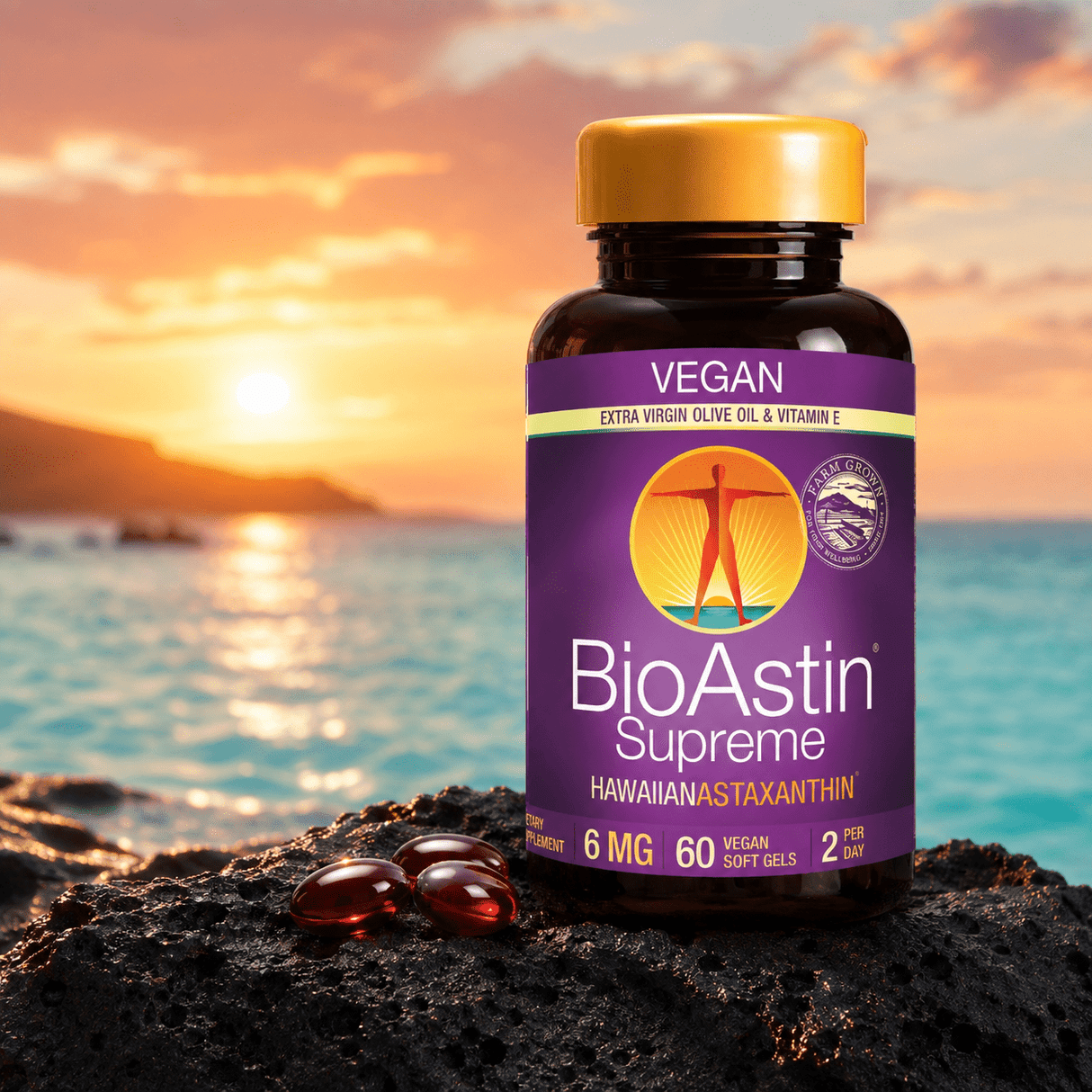 BioAstin Supreme astaxantin i en brun plastflaske med gul lokk, seks røde softgels på svart stein, horisont med solnedgang.