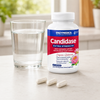 Candidase® Extra Strength i hvit beholder, med tre kapsler i nærheten av et glass med vann.