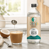 Go-Keto MCT olje Pure C8 i en gjennomsiktig flaske, helles i en kopp med kaffe på en kjøkkenbenk.
