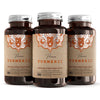 Tre brune flasker med vegetabilske kapsler, etikett med teksten "Premium Turmeric" og oransje detaljering.